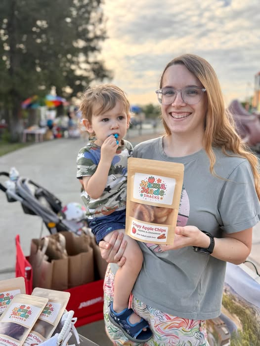 Founder holding a Mama Made Snacks bag with her child outdoors